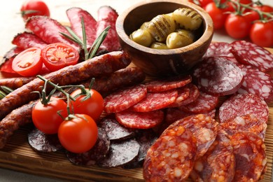 Photo of Different smoked sausages slices served on light table, closeup