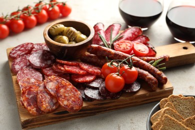 Photo of Different smoked sausages slices served on light table, closeup