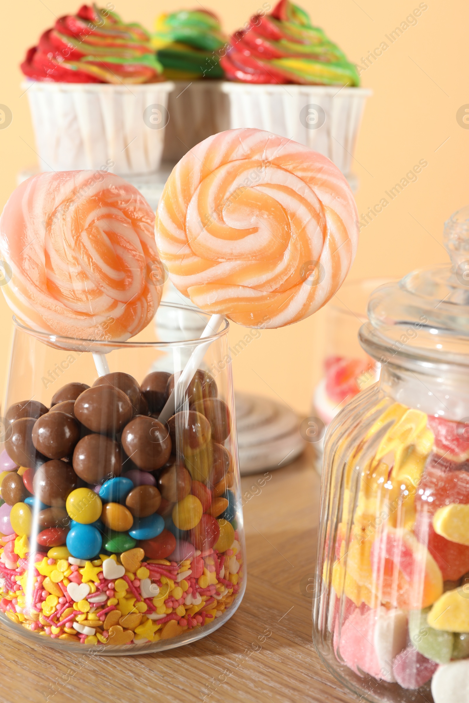 Photo of Candy bar. Many different sweets on wooden table against beige background, closeup