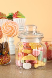 Photo of Candy bar. Many different sweets on wooden table against beige background, closeup