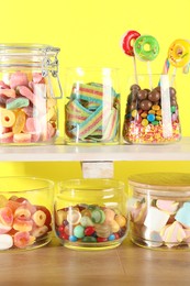 Photo of Candy bar. Many different sweets on wooden table against yellow background