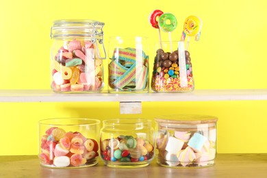 Photo of Candy bar. Many different sweets on wooden table against yellow background