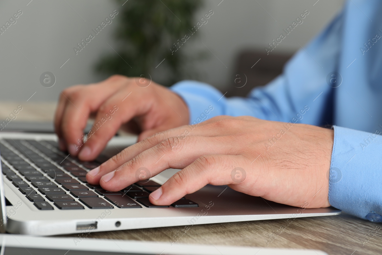 Photo of Businessman using laptop at wooden table, closeup. Modern technology