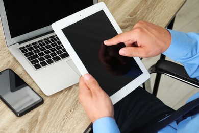 Photo of Businessman with tablet, smartphone and laptop at wooden table, closeup. Modern technology