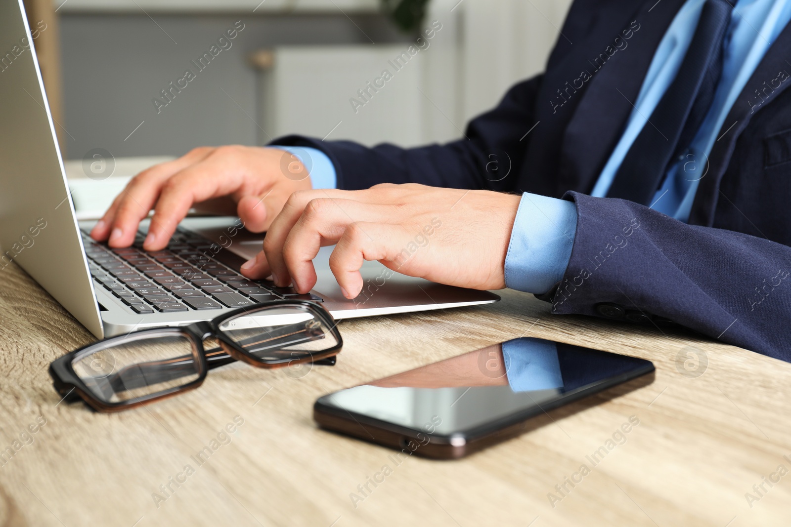 Photo of Businessman using laptop at wooden table, closeup. Modern technology