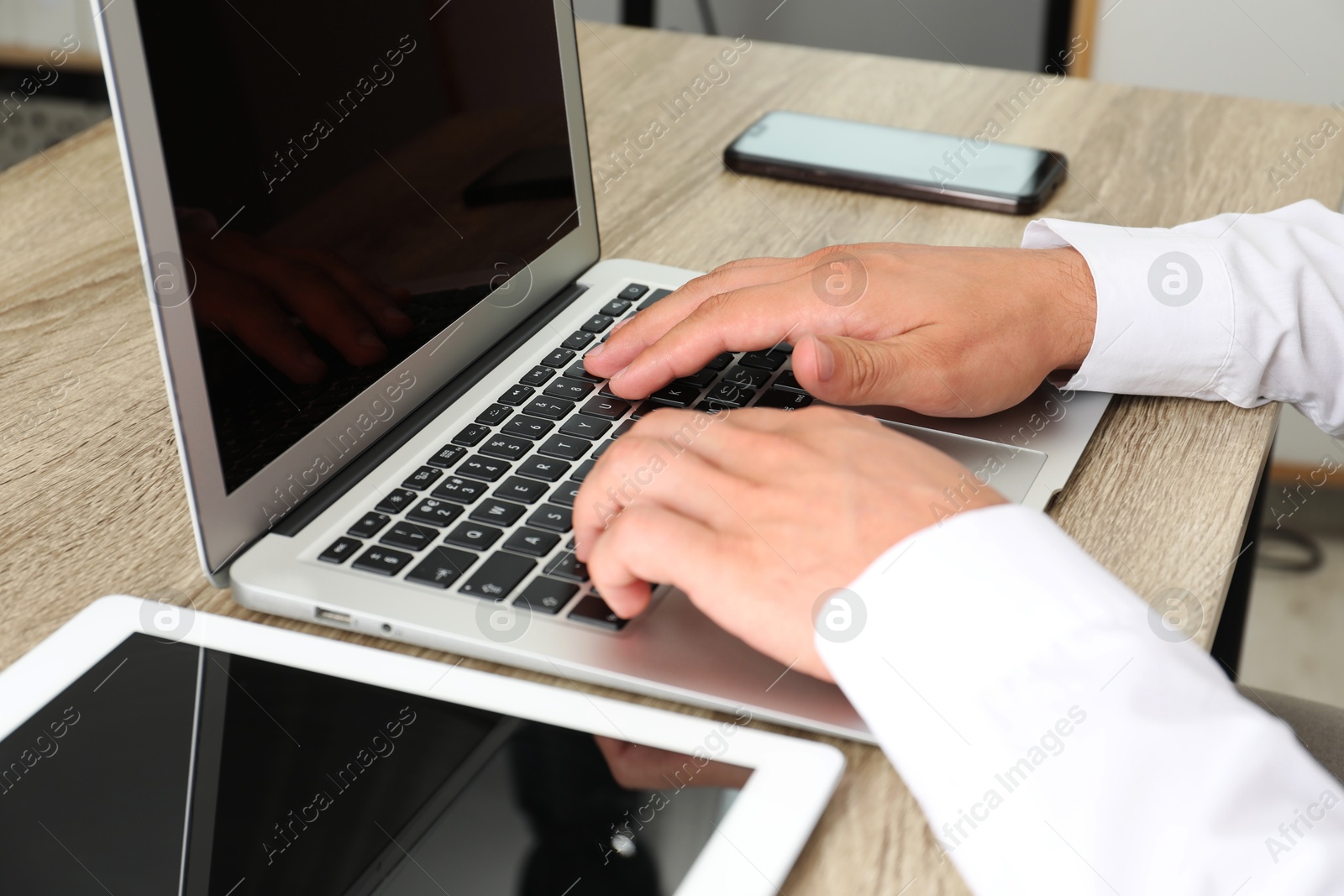 Photo of Businessman using laptop at wooden table, closeup. Modern technology