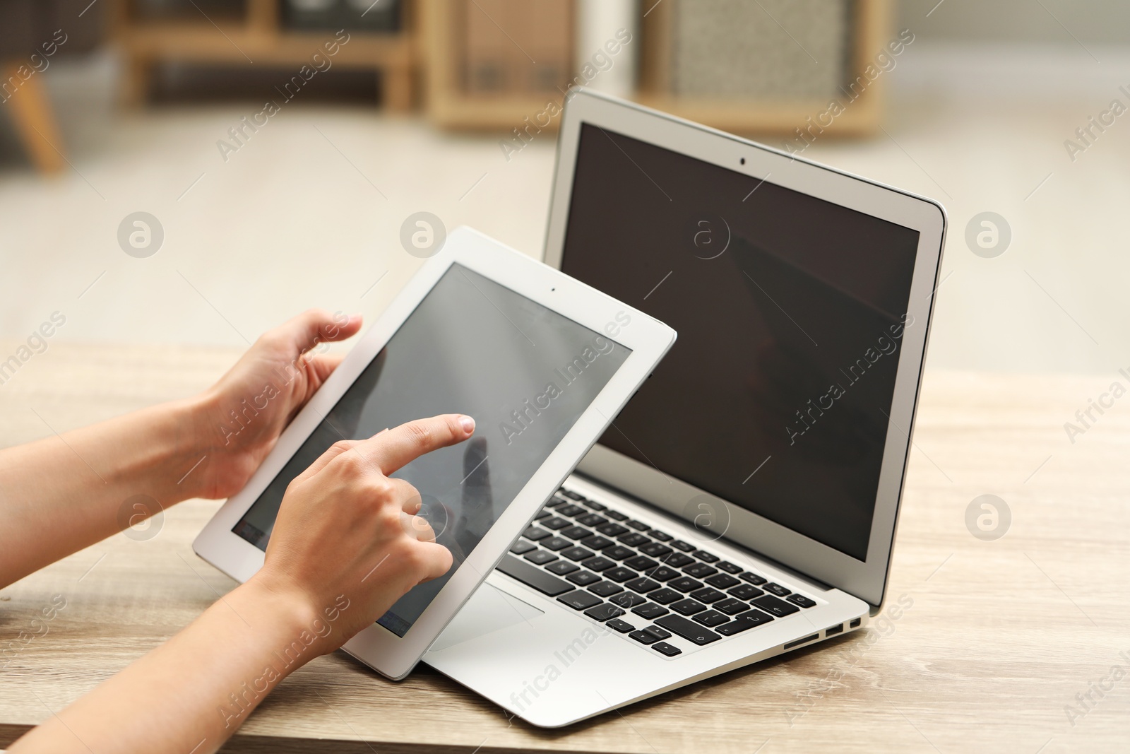 Photo of Businessman with tablet and laptop at wooden table, closeup. Modern technology