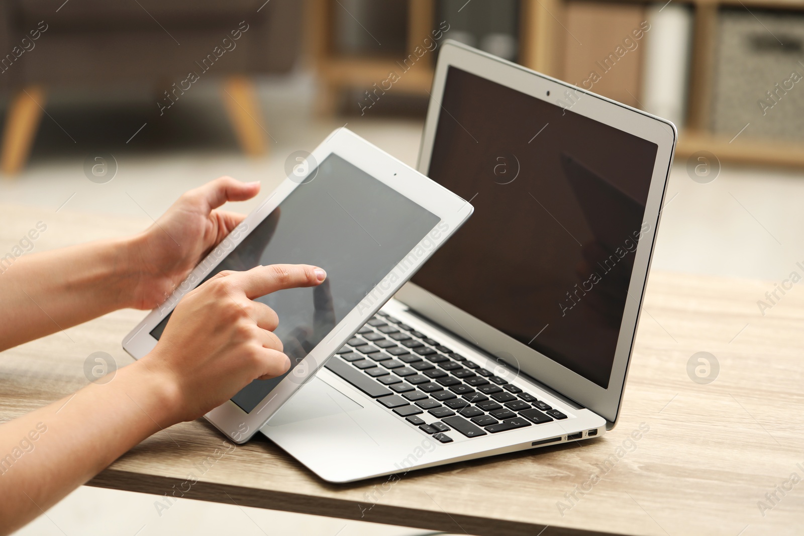 Photo of Businessman with tablet and laptop at wooden table, closeup. Modern technology