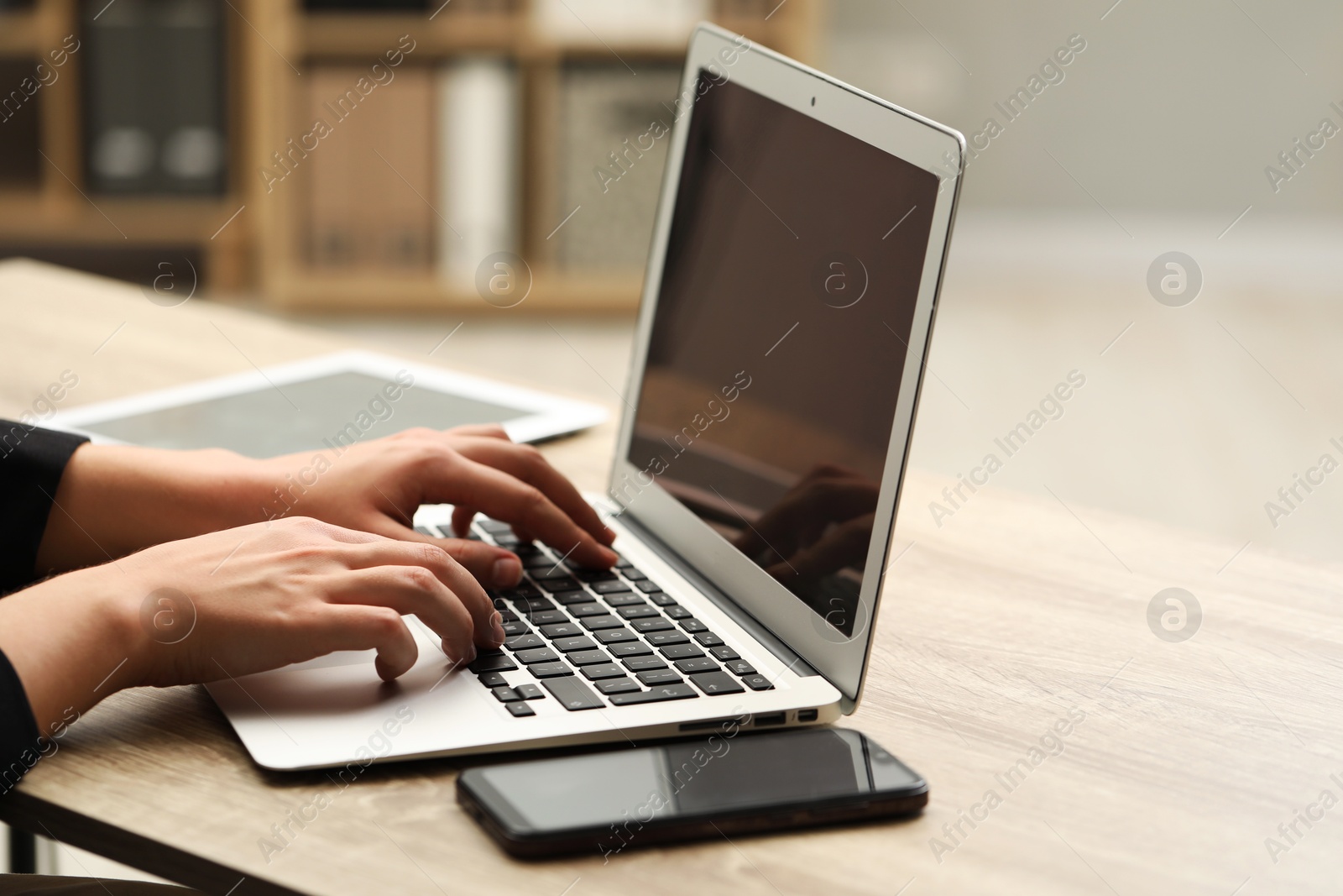 Photo of Businessman using laptop at wooden table, closeup. Modern technology