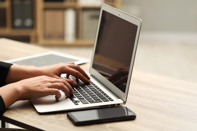 Photo of Businessman using laptop at wooden table, closeup. Modern technology