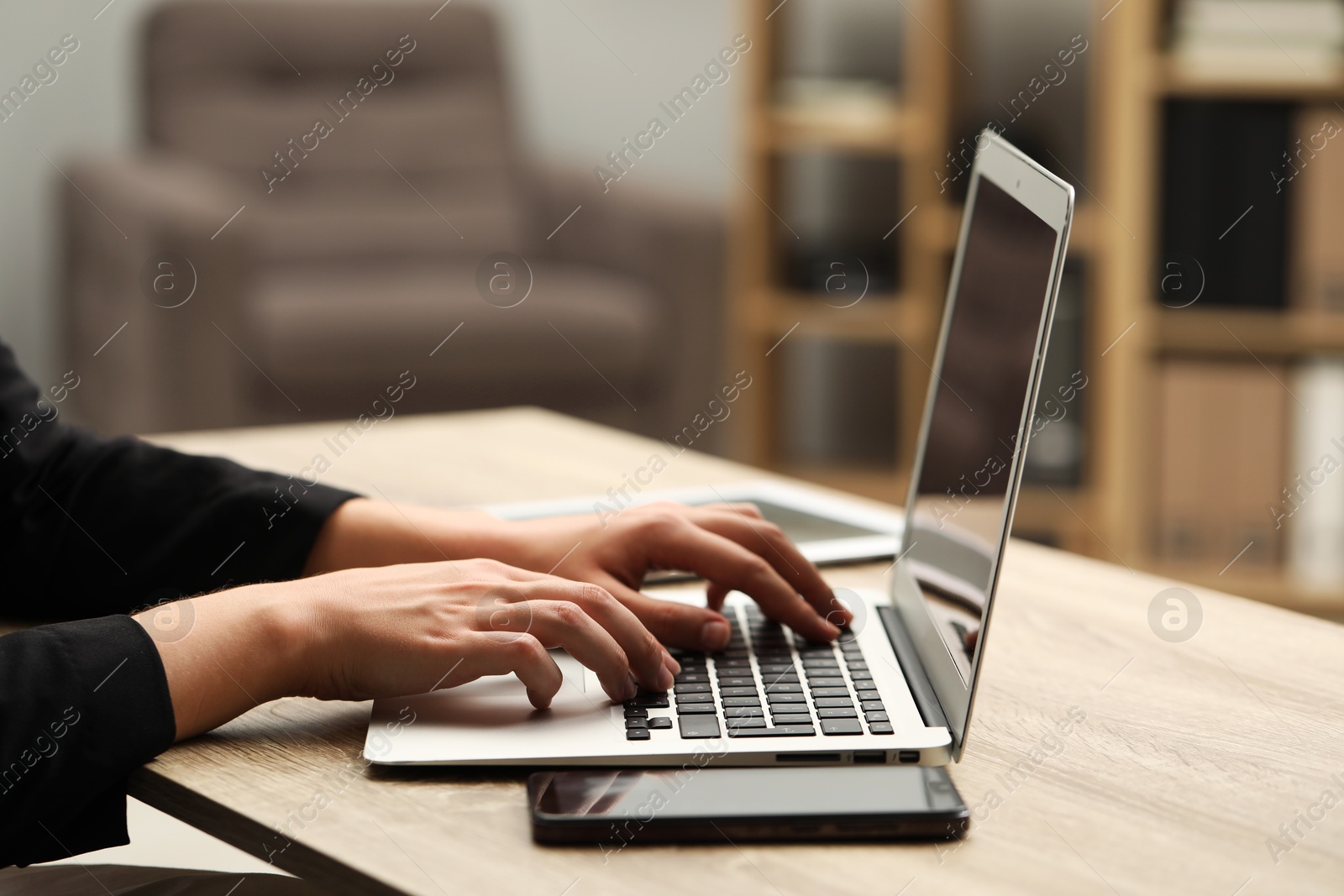 Photo of Businessman using laptop at wooden table, closeup. Modern technology