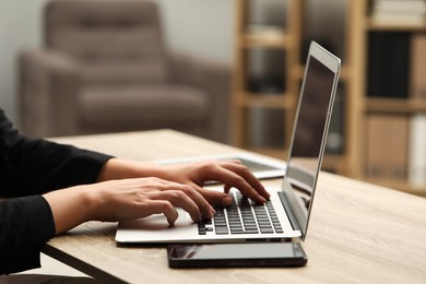 Photo of Businessman using laptop at wooden table, closeup. Modern technology