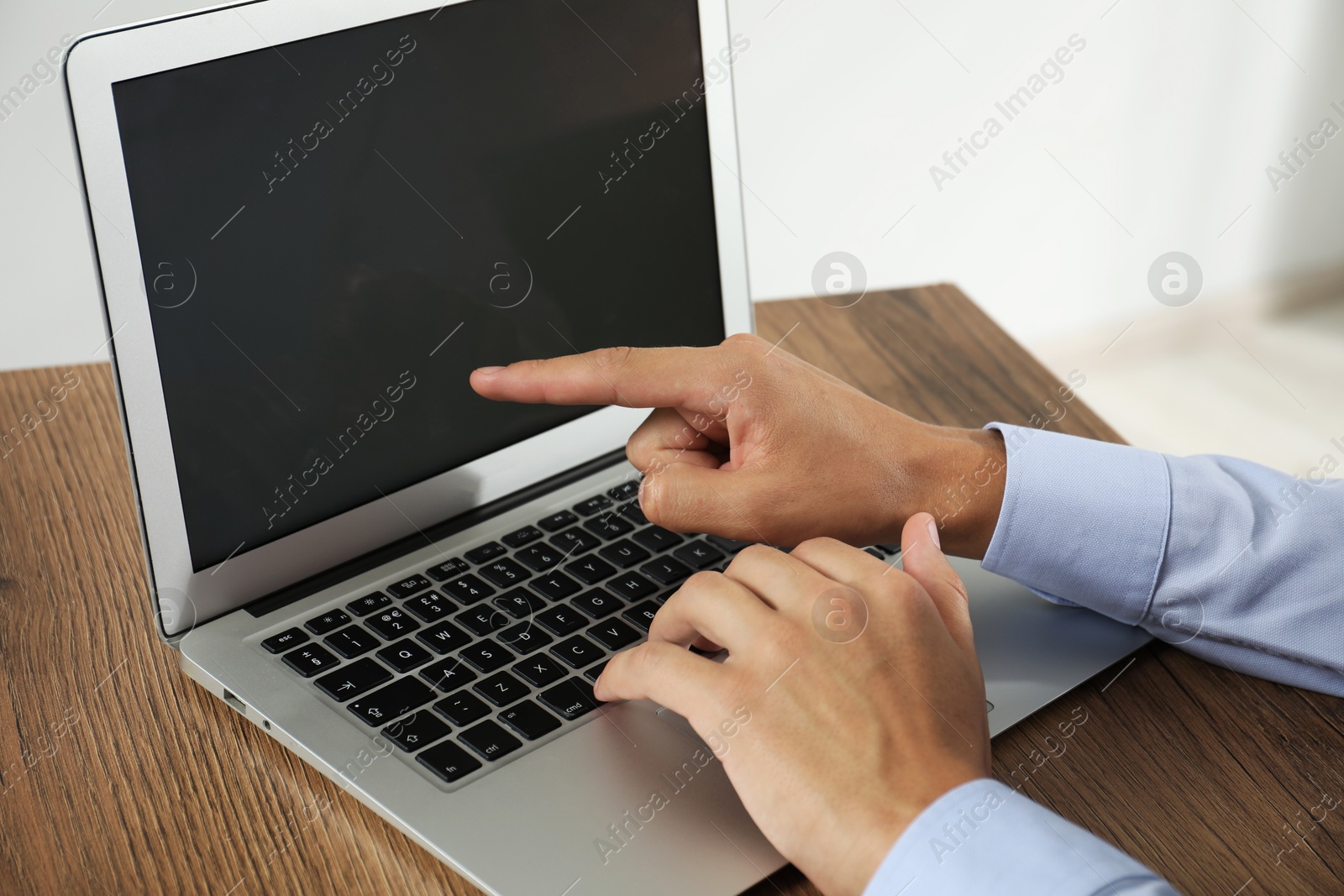 Photo of Businessman using laptop at wooden table, closeup. Modern technology