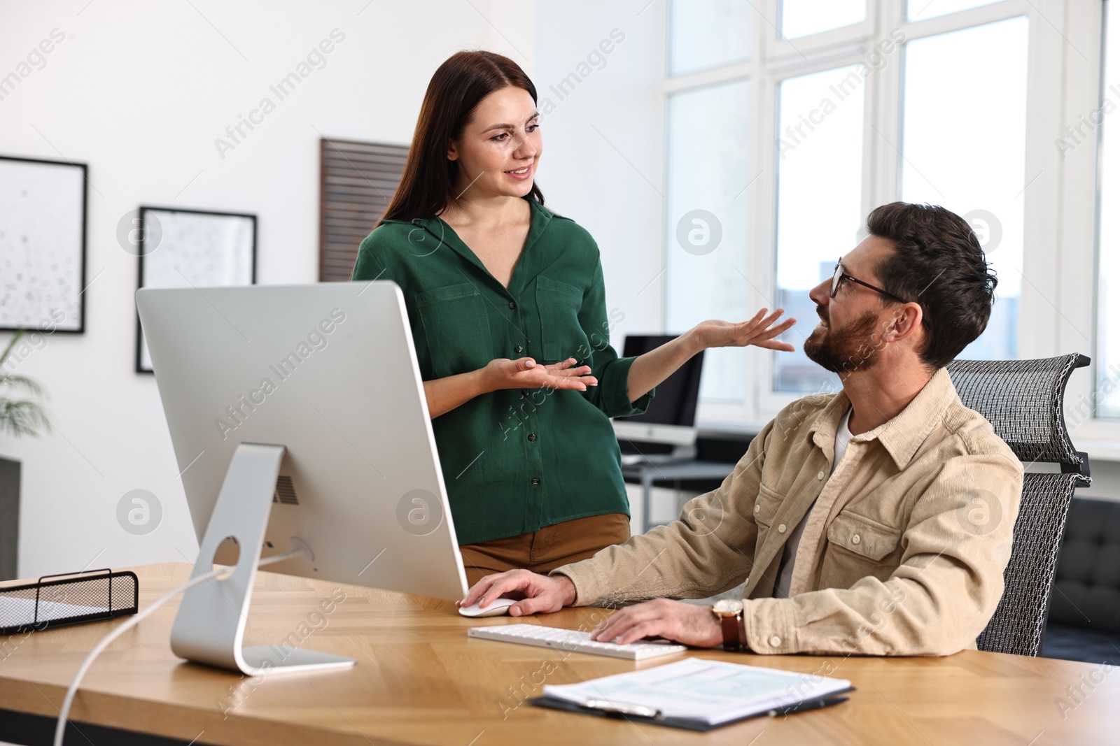 Photo of Colleagues working with computer at desk in office