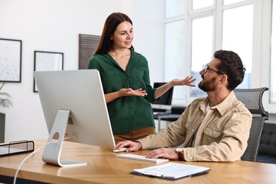 Photo of Colleagues working with computer at desk in office