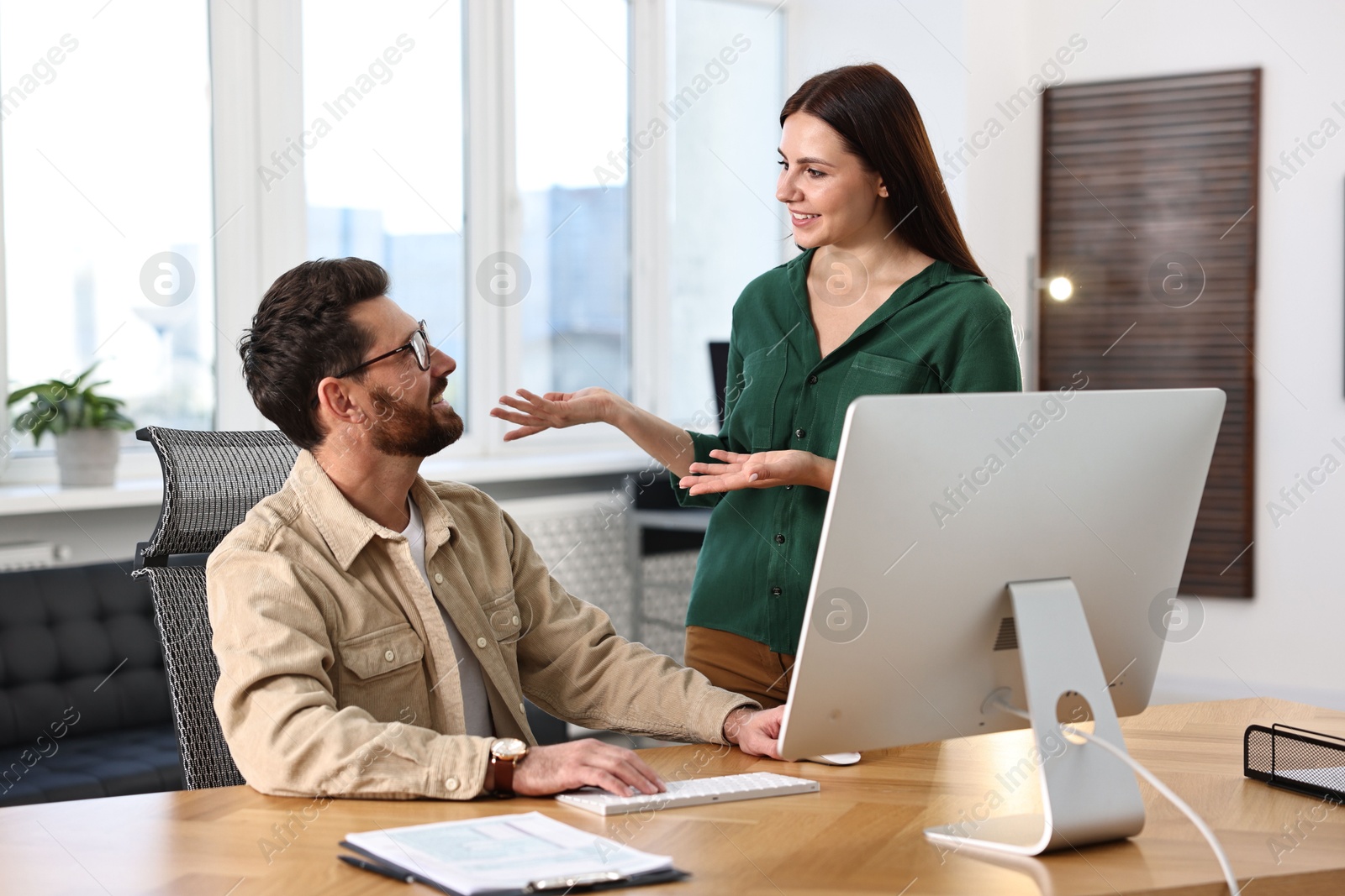 Photo of Colleagues working with computer at desk in office