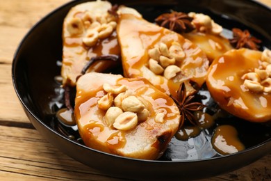 Photo of Delicious pears with caramel sauce, nuts and anise stars on wooden table, closeup