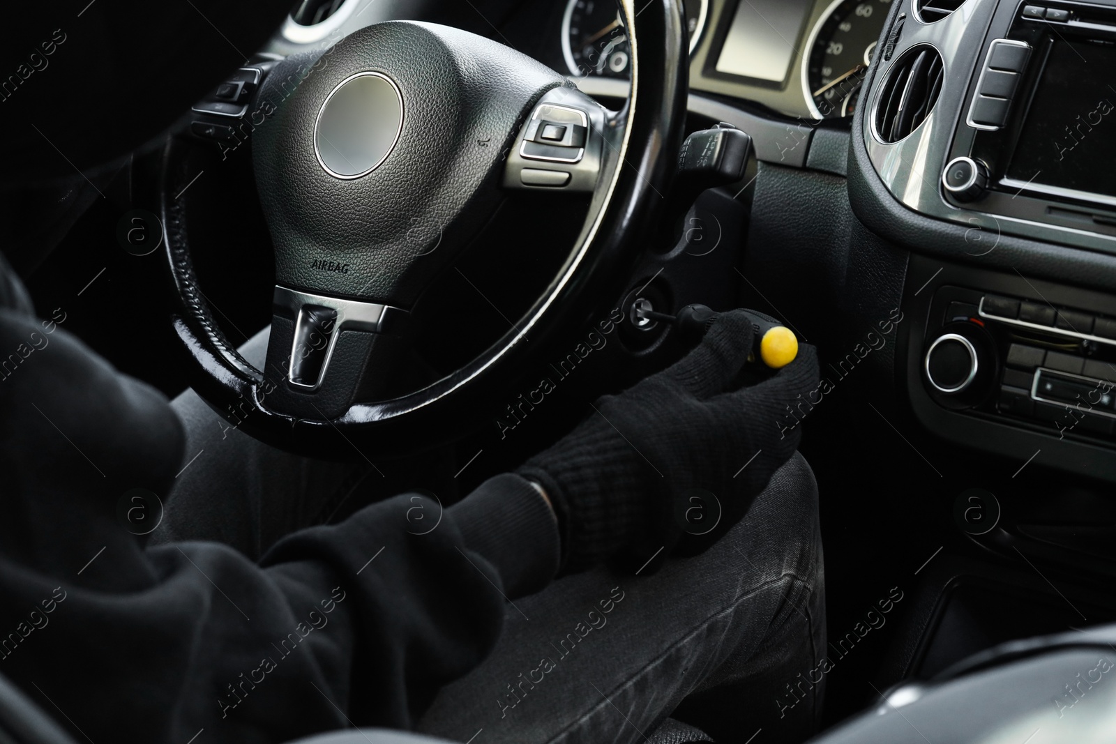 Photo of Thief trying to start ignition switch with screwdriver, closeup. Car hijacking