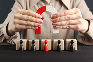 Photo of Woman with magnet attracting game pieces at wooden table, closeup