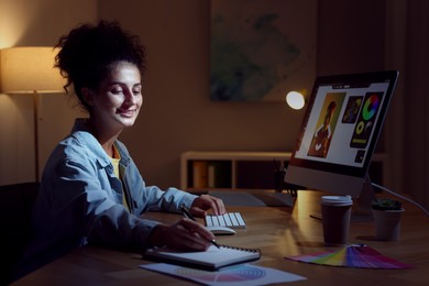 Photo of Designer with notebook working indoors at night