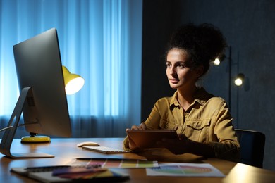 Photo of Designer with tablet working indoors at night