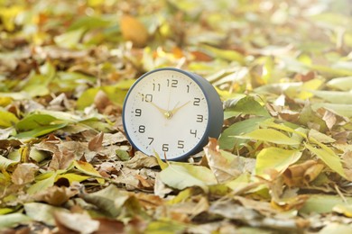 Photo of Autumn time. Alarm clock on fallen leaves