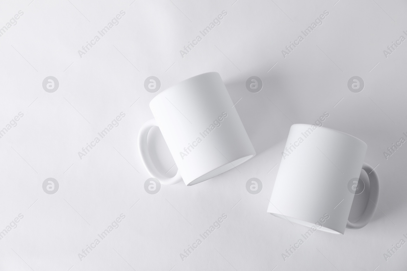 Photo of Two blank mugs on white background, top view. Mockup for design