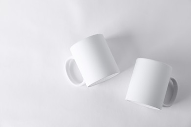 Photo of Two blank mugs on white background, top view. Mockup for design