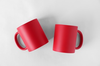 Photo of Two blank red mugs on white background, top view. Mockup for design