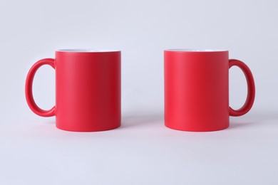 Photo of Two blank red mugs on white background. Mockup for design