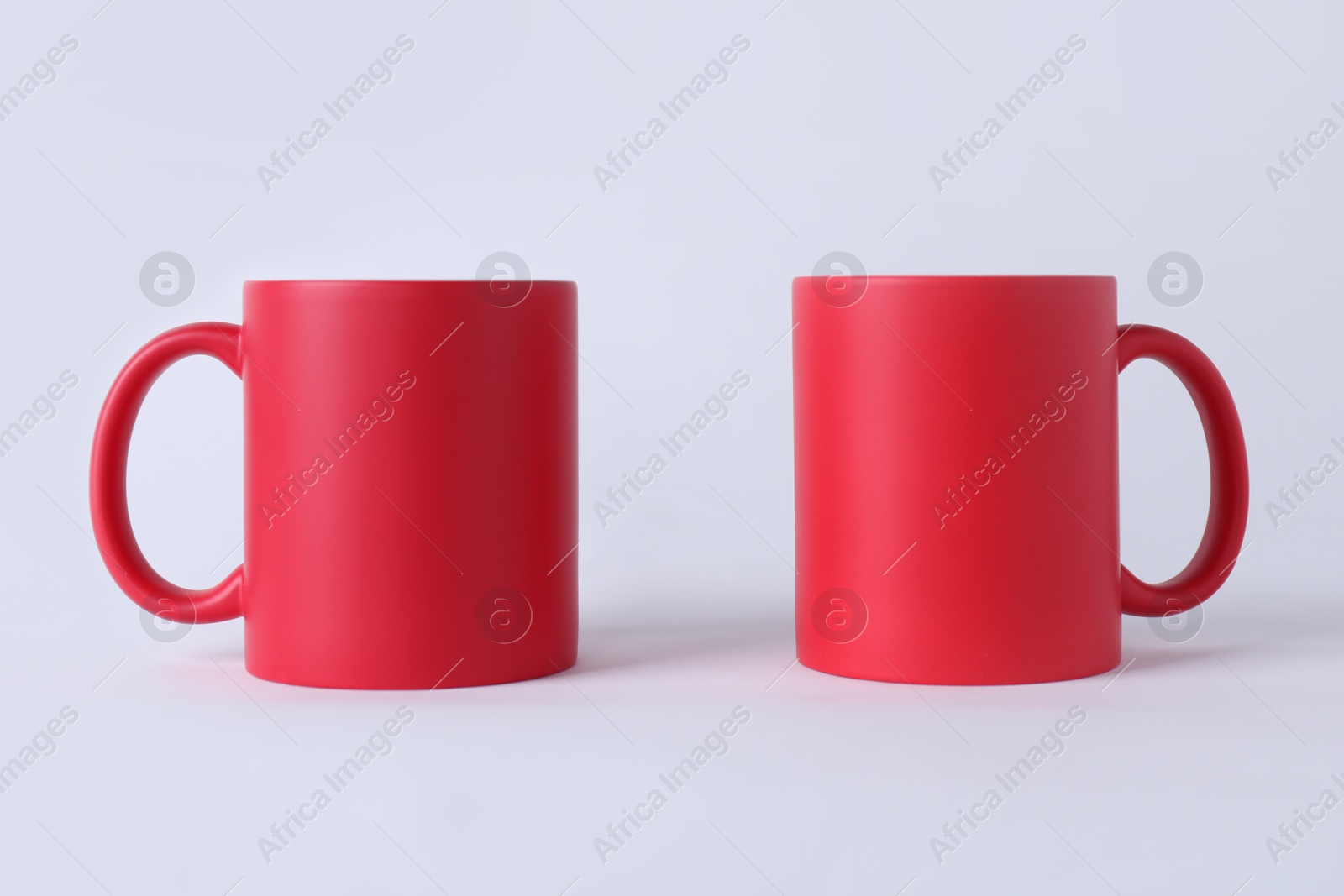 Photo of Two blank red mugs on white background. Mockup for design