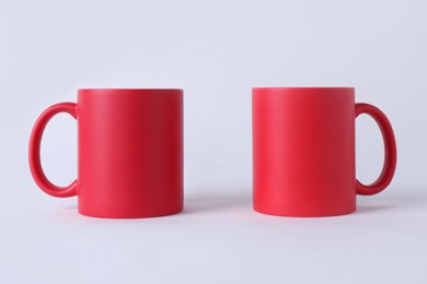 Photo of Two blank red mugs on white background. Mockup for design