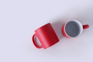 Photo of Two blank red mugs on white background, top view. Mockup for design