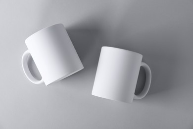 Photo of Two blank white mugs on light background, top view. Mockup for design