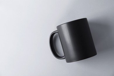 Photo of One blank black mug on light background, top view. Mockup for design