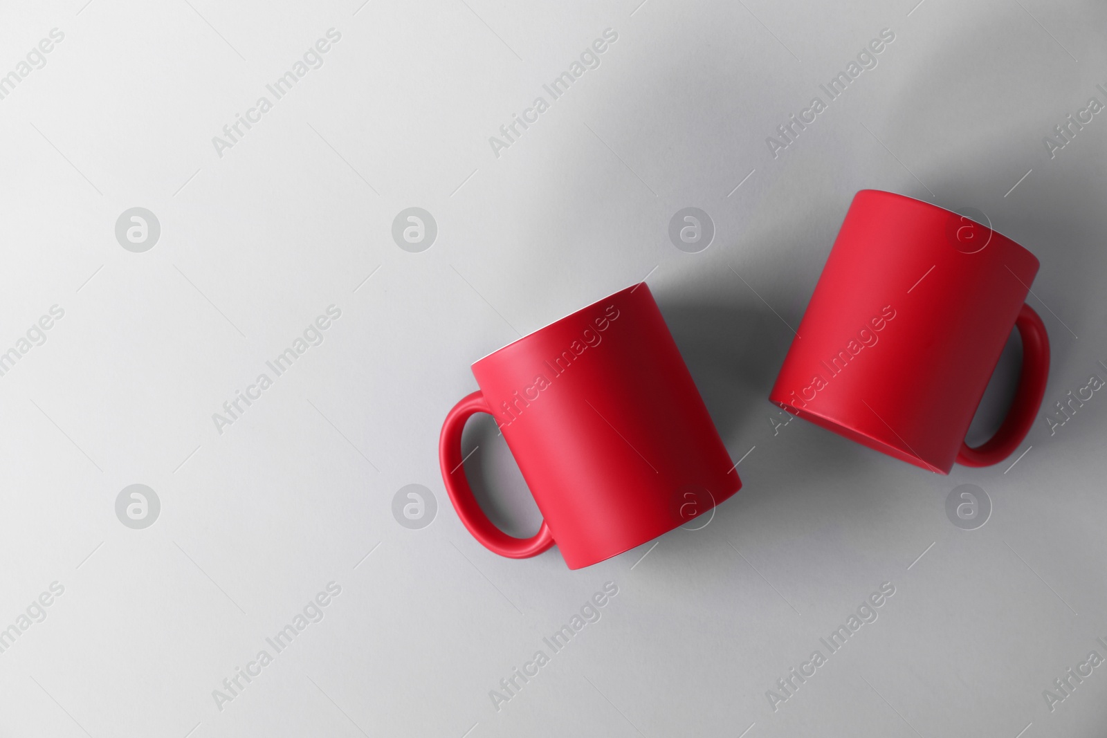 Photo of Two blank red mugs on light background, top view. Mockup for design