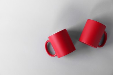 Photo of Two blank red mugs on light background, top view. Mockup for design