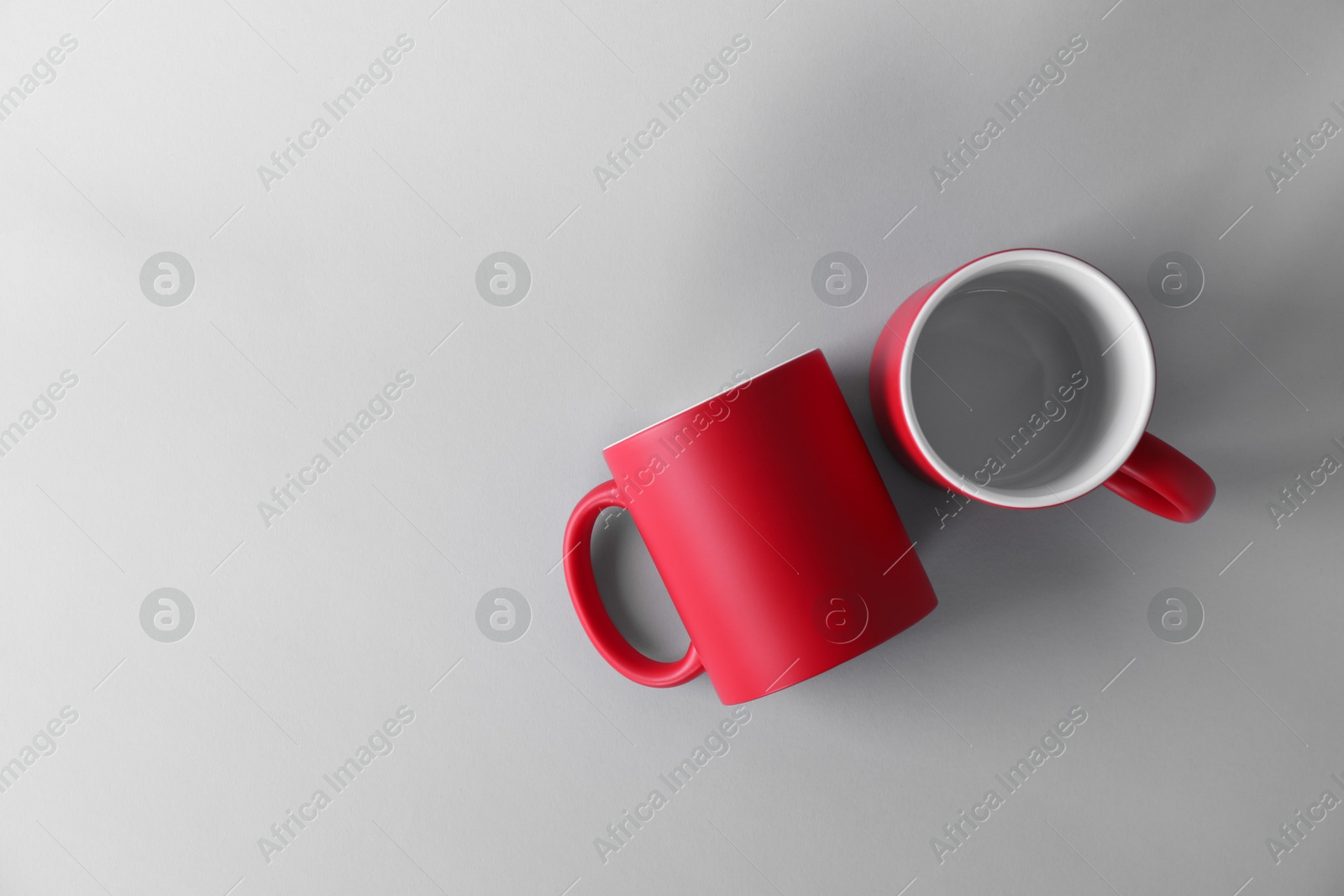 Photo of Two blank red mugs on light background, top view. Mockup for design