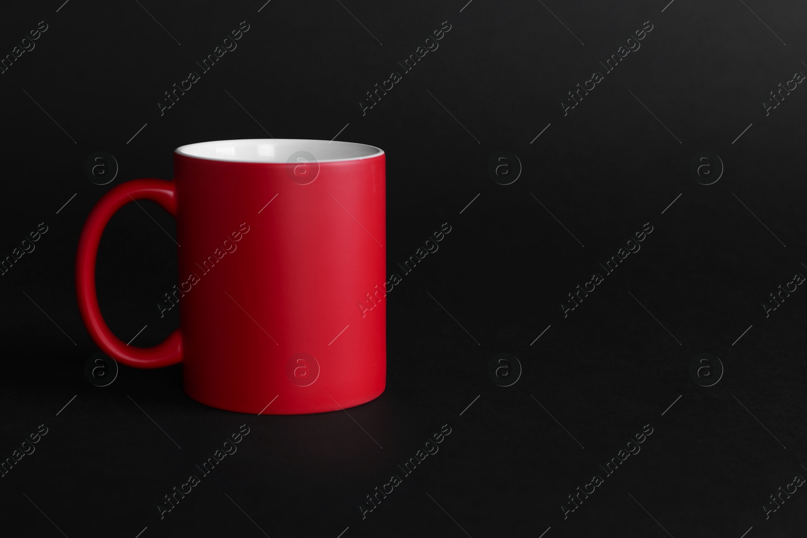 Photo of One blank red mug on black background. Mockup for design