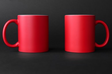 Two blank red mugs on black background. Mockup for design