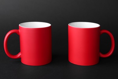 Two blank red mugs on black background. Mockup for design