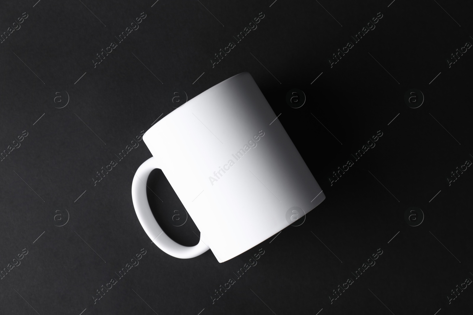 Photo of One blank white mug on black background, top view. Mockup for design