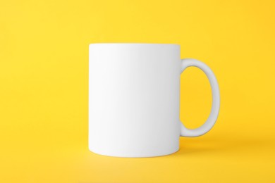 Photo of One blank white mug on yellow background. Mockup for design