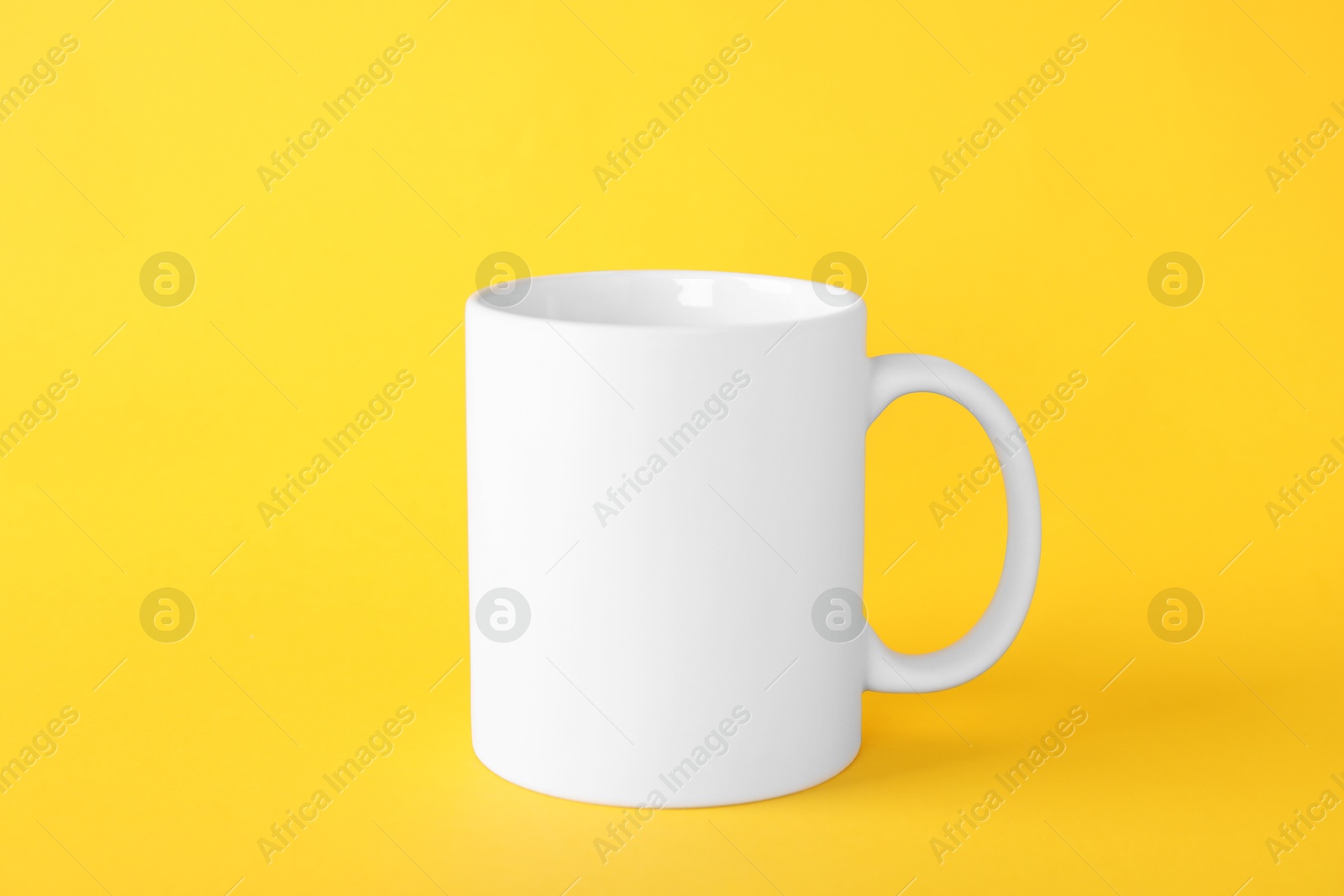 Photo of One blank white mug on yellow background. Mockup for design