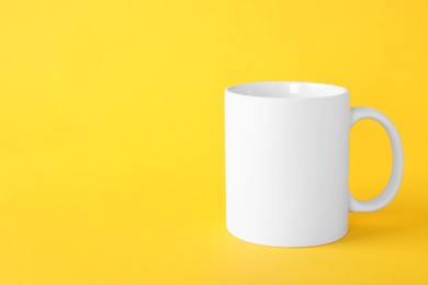 Photo of One blank white mug on yellow background. Mockup for design