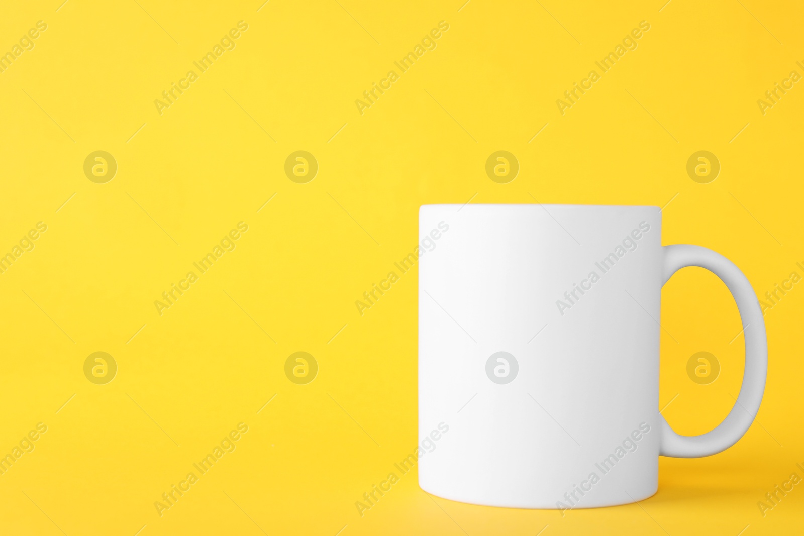 Photo of One blank white mug on yellow background. Mockup for design