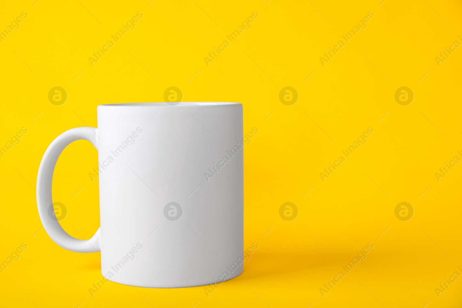 Photo of One blank white mug on yellow background. Mockup for design