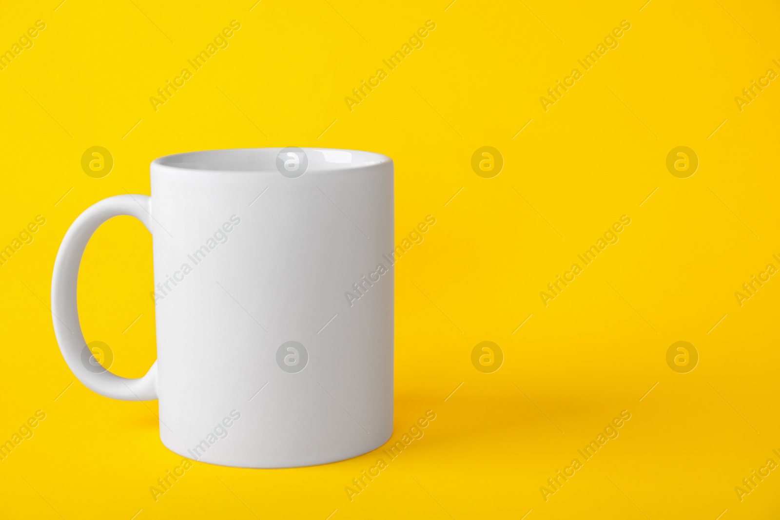 Photo of One blank white mug on yellow background. Mockup for design