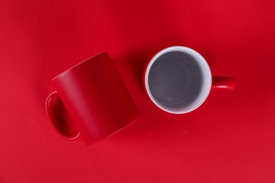 Photo of Two blank mugs on red background, top view. Mockup for design