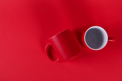 Photo of Two blank mugs on red background, top view. Mockup for design